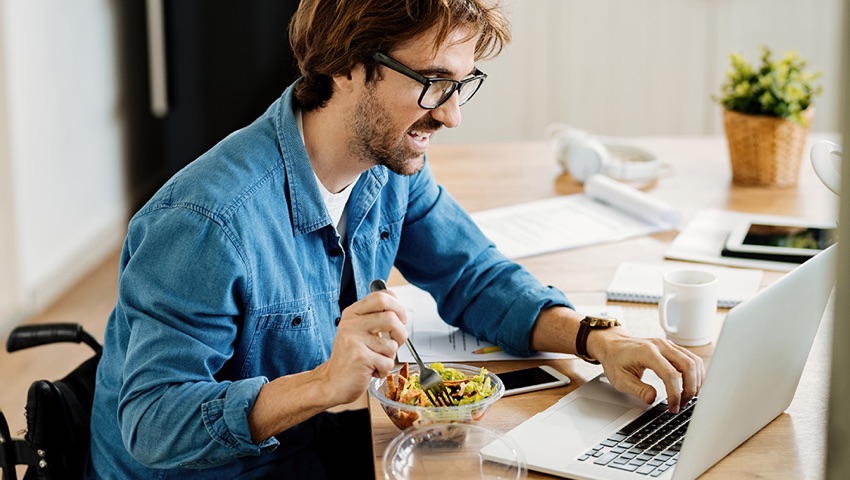 Man eating while working on laptop